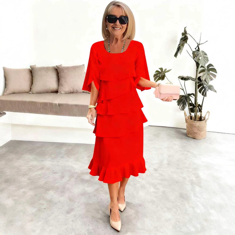 Woman in a red dress holding a pink clutch in a modern living room.