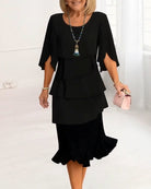 Woman wearing a black dress with ruffled layers on a white background