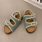 Pair of green sandals with white straps on a gray surface