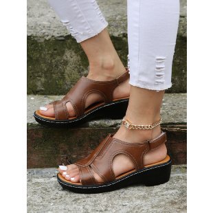Brown sandals worn with white pants on a stone surface