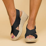 Black wedge sandals with espadrille sole on a beige background
