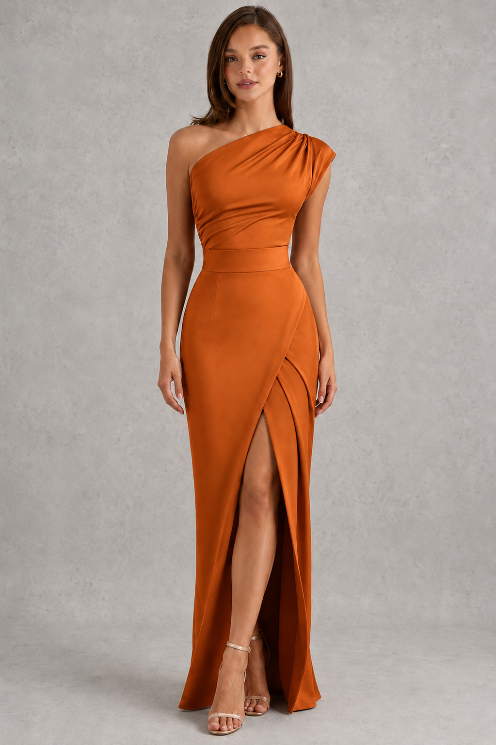 Woman wearing a one-shoulder orange dress with a slit on a gray background