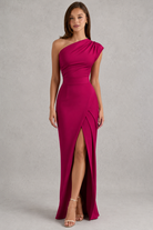 Woman wearing a magenta one-shoulder dress with a slit on a gray background