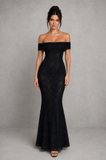 Woman wearing a black off-shoulder lace gown against a gray background
