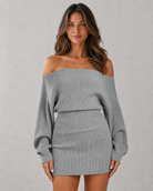 Woman wearing a gray off-shoulder sweater dress against a plain background