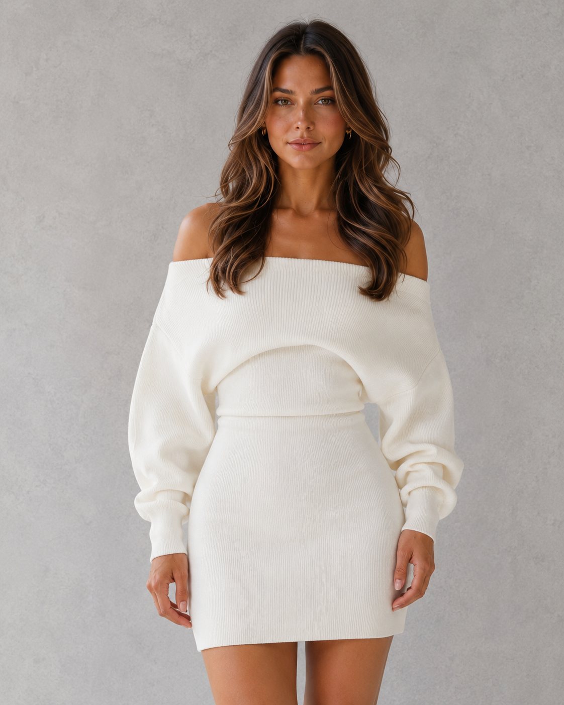 Woman wearing a white off-shoulder sweater dress against a gray background
