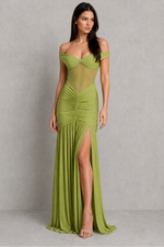 Woman wearing a green evening gown with a high slit on a gray background