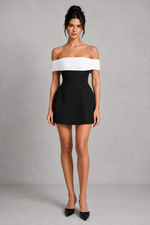 Woman wearing a black and white off-shoulder dress on a gray background