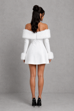 Woman wearing a white off-shoulder dress with fur trim against a gray background