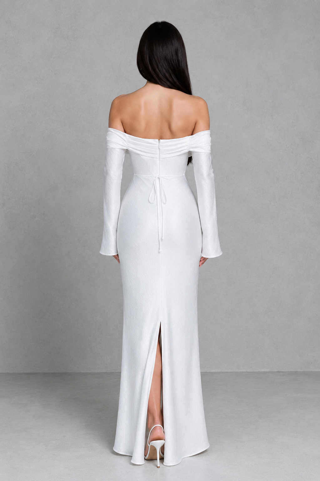 Woman wearing a white off-shoulder gown with a high slit on a gray background