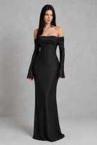 Woman wearing a black off-shoulder gown against a gray background