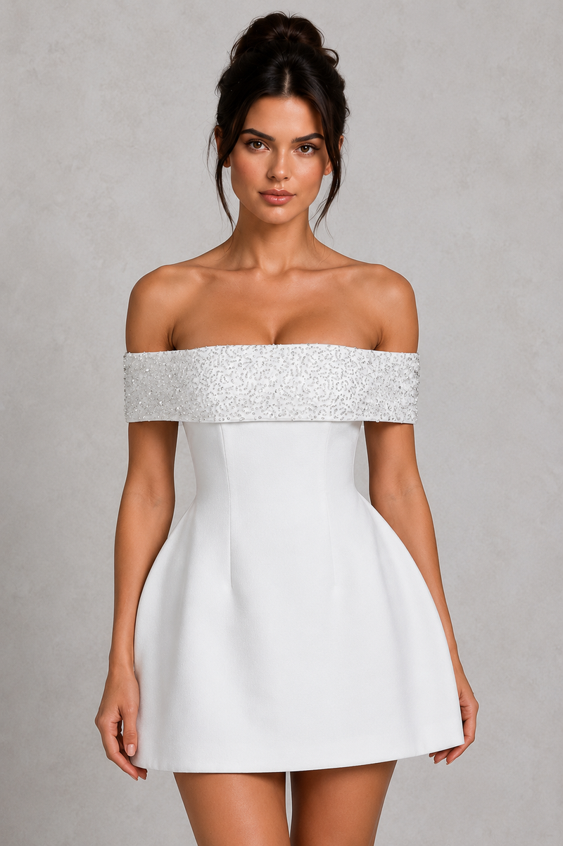 Woman wearing a white off-shoulder dress with a beaded neckline on a gray background