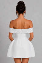 White off-shoulder dress with silver embellishments on a gray background