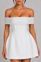 White off-shoulder dress with silver embellishments on a gray background