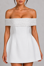 White off-shoulder dress with silver embellishments on a gray background