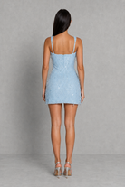 Woman wearing a light blue denim dress against a gray background