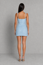Woman wearing a light blue denim dress against a gray background