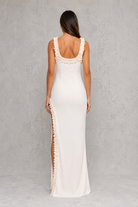 Woman wearing a white dress with lace details on a gray background