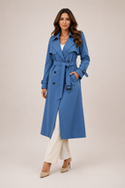 Woman wearing a blue trench coat on a beige background