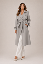 Woman wearing a gray trench coat on a plain background
