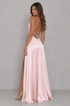 Woman wearing a pink evening gown with a backless design against a gray background