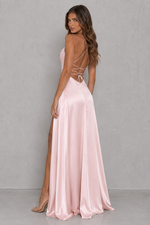 Woman wearing a pink evening gown with a backless design against a gray background
