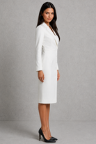 Woman wearing a white suit against a gray background