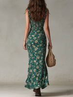 Woman wearing a green floral dress holding a woven bag against a neutral background
