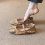 Beige woven shoes worn by a person on a beige carpet
