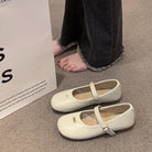 White shoes with a strap on a carpeted floor next to a white box.