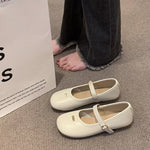 White shoes with a strap on a carpeted floor next to a white box.