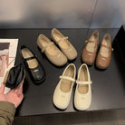Set of black, beige, and brown shoes on a dark surface with a hand holding a shoe.