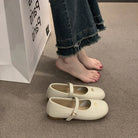 White shoes on a carpeted floor with a person wearing jeans and standing next to a box.