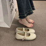 White shoes on a carpeted floor with a person wearing jeans and standing next to a box.