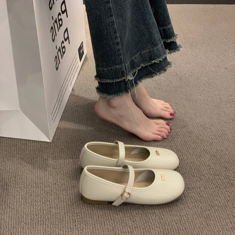 White shoes on a carpeted floor with a person wearing jeans and standing next to a box.