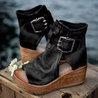 Black wedge sandals with wooden soles on a wooden surface with a blurred natural background