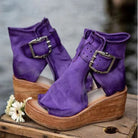 Purple wedge sandals with wooden soles on a rustic wooden surface.
