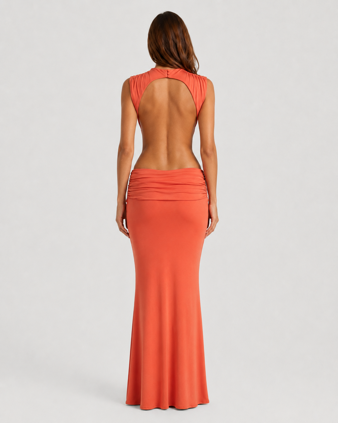 Woman wearing a long orange dress with a plain background