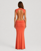Woman wearing a long orange dress with a plain background
