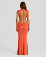 Woman wearing a long orange dress with a plain background