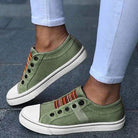 Green casual sneakers worn with light blue jeans on a pavement background
