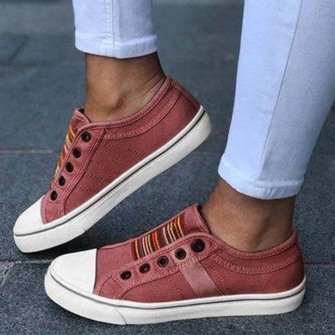 Red sneakers with white soles worn with light blue jeans on a dark surface