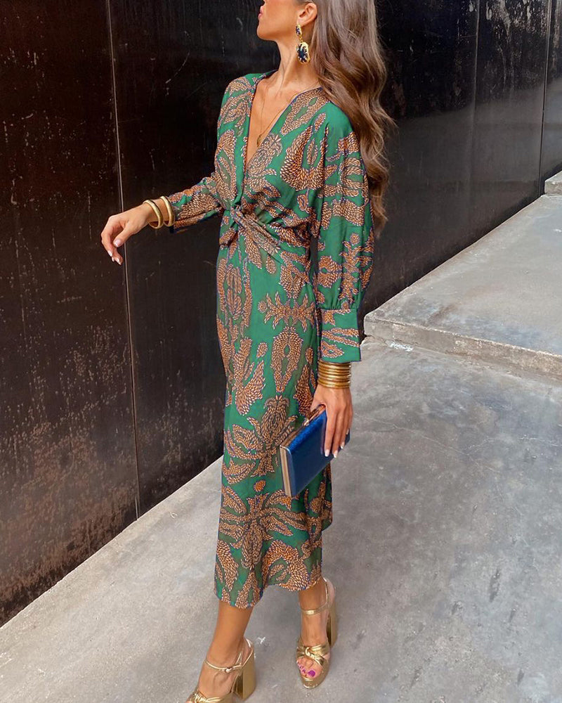 Woman in a green patterned dress standing against a black wall.