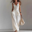 Woman wearing a white sleeveless jumpsuit with a plain background