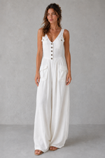 Woman wearing a white sleeveless dress with buttons on a gray background