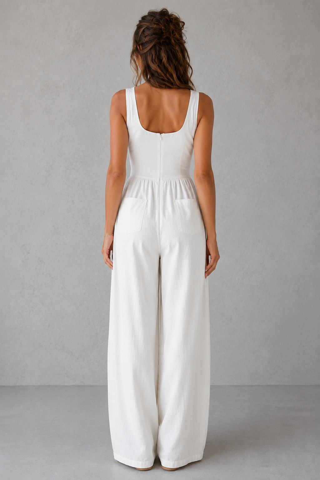 Woman wearing a white jumpsuit against a plain background