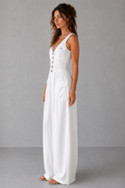 Woman wearing a white dress with buttons on a gray background