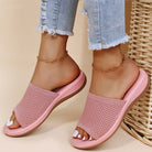 Pink sandals worn with light blue jeans on a beige background