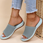 Gray sandals worn with light blue jeans on a beige background