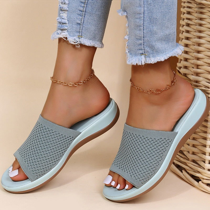 Gray sandals worn with light blue jeans on a beige background